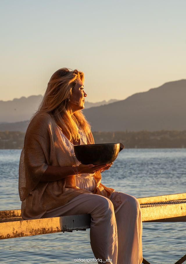 Gaëlle assise au bord du lac avec un bol chantant