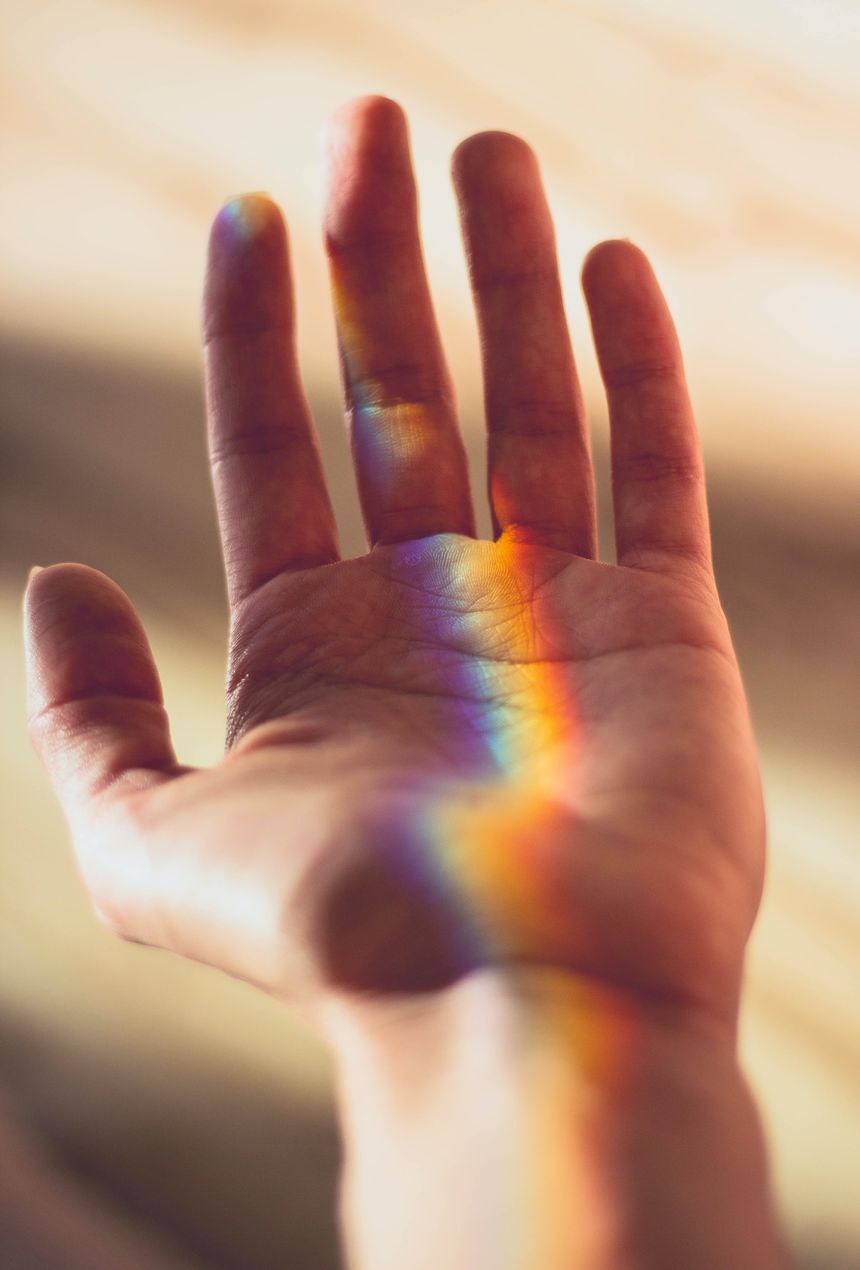 Main ouverte traversée par un arc-en-ciel de lumière